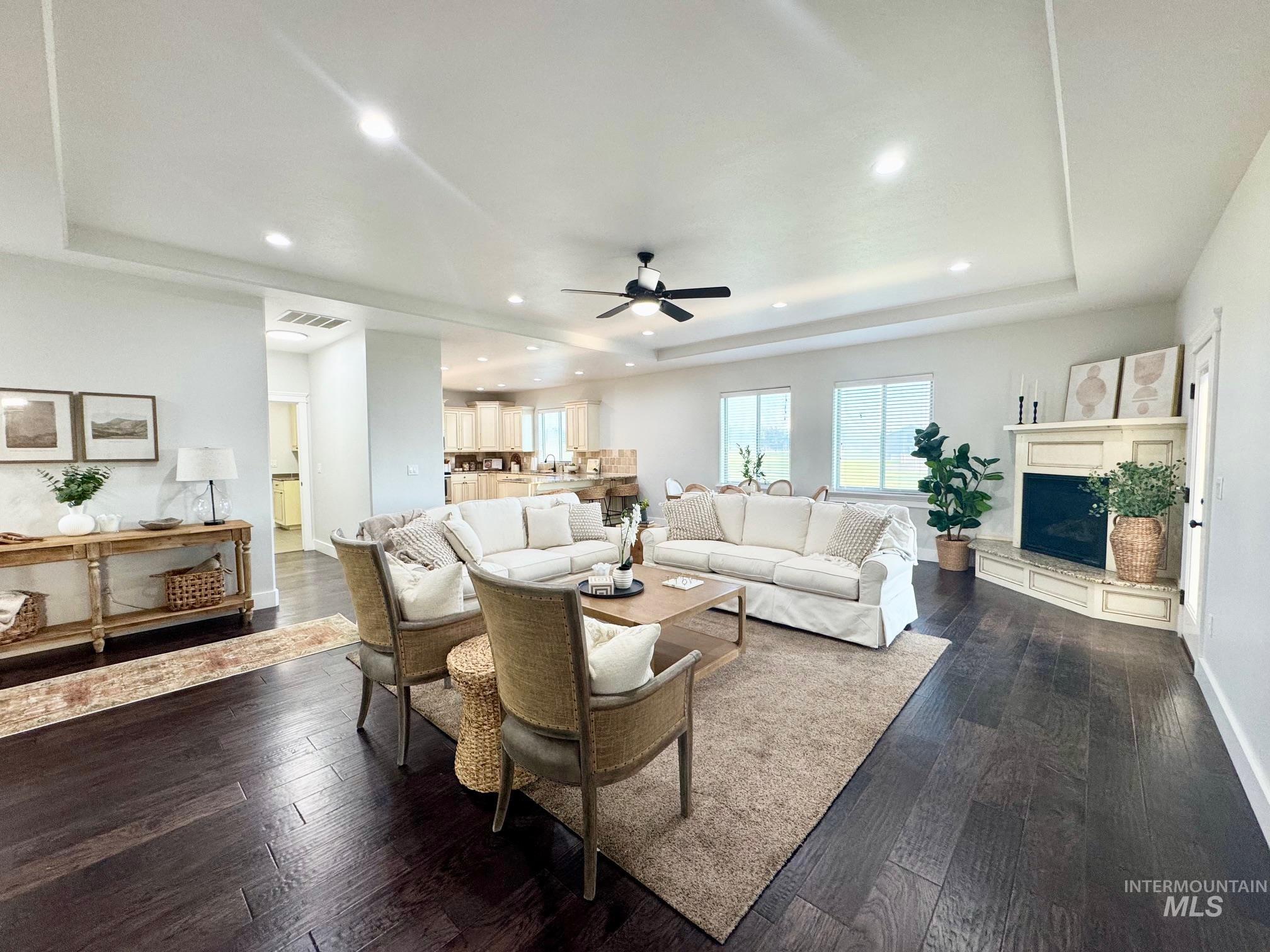 650 Lochsa Loop Heyburn, ID 83336 - Photo 5 of 26 Living room with a raised ceiling, dark wood-type flooring, recessed lighting, a fireplace with raised hearth, and ceiling fan