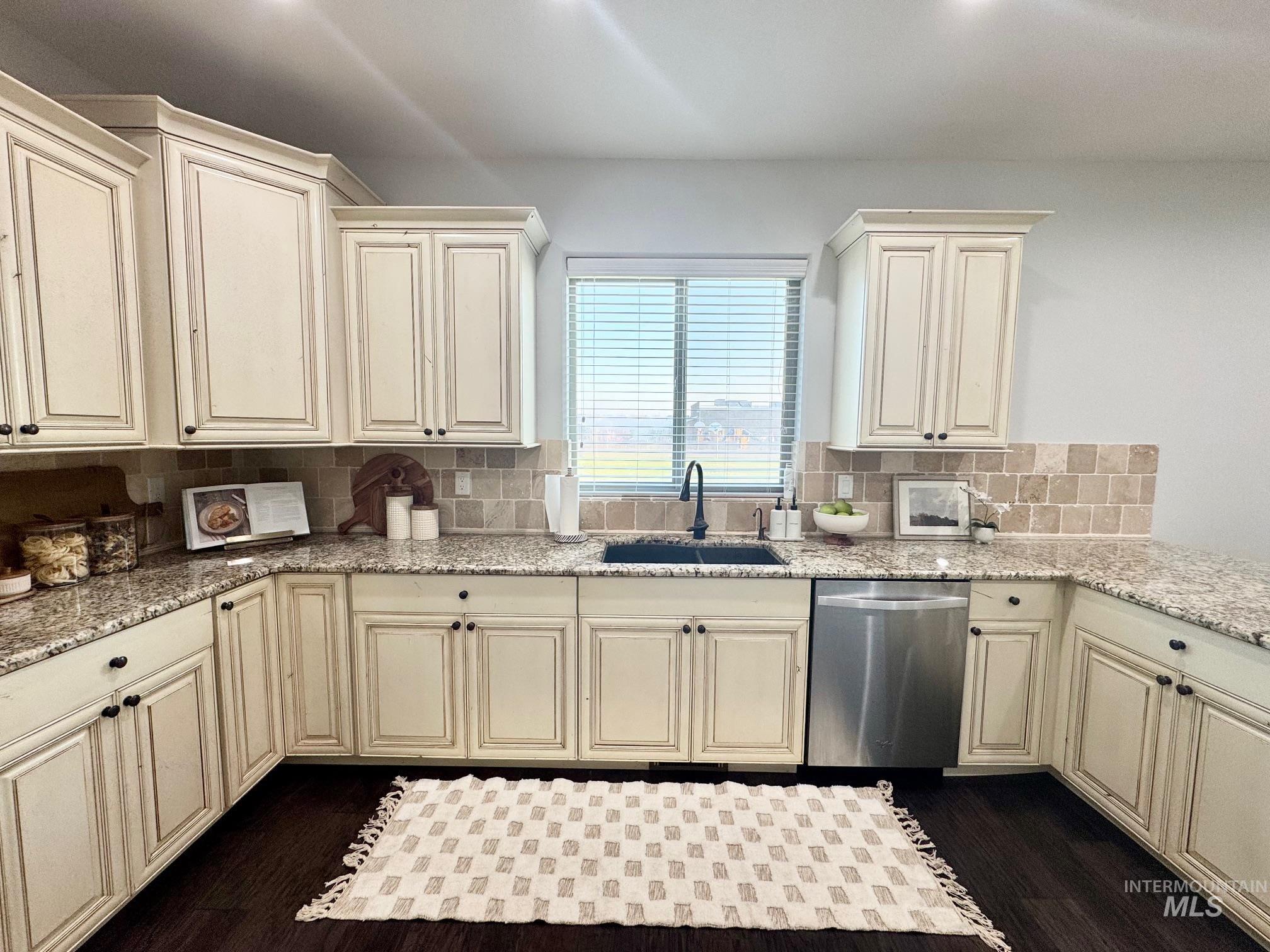 650 Lochsa Loop Heyburn, ID 83336 - Photo 9 of 26 Kitchen featuring cream cabinetry, dishwasher, decorative backsplash, light stone counters, and dark wood-type flooring