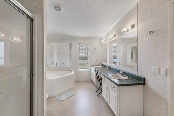 a bathroom with a granite countertop double vanity sink a mirror and a bathtub