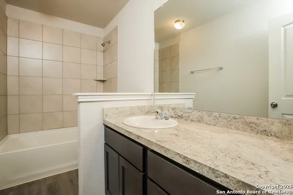 a bathroom with a granite countertop sink a mirror and a bathtub