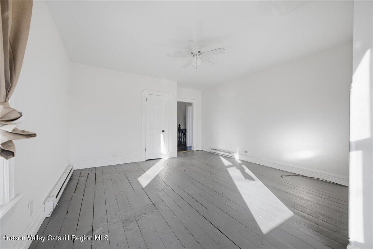 97 Maple Avenue Catskill, NY 12414 - Photo 12 of 27 an empty room with wooden floor and windows