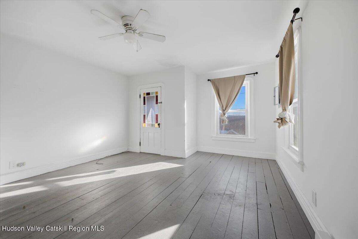 97 Maple Avenue Catskill, NY 12414 - Photo 8 of 27 an empty room with wooden floor and windows