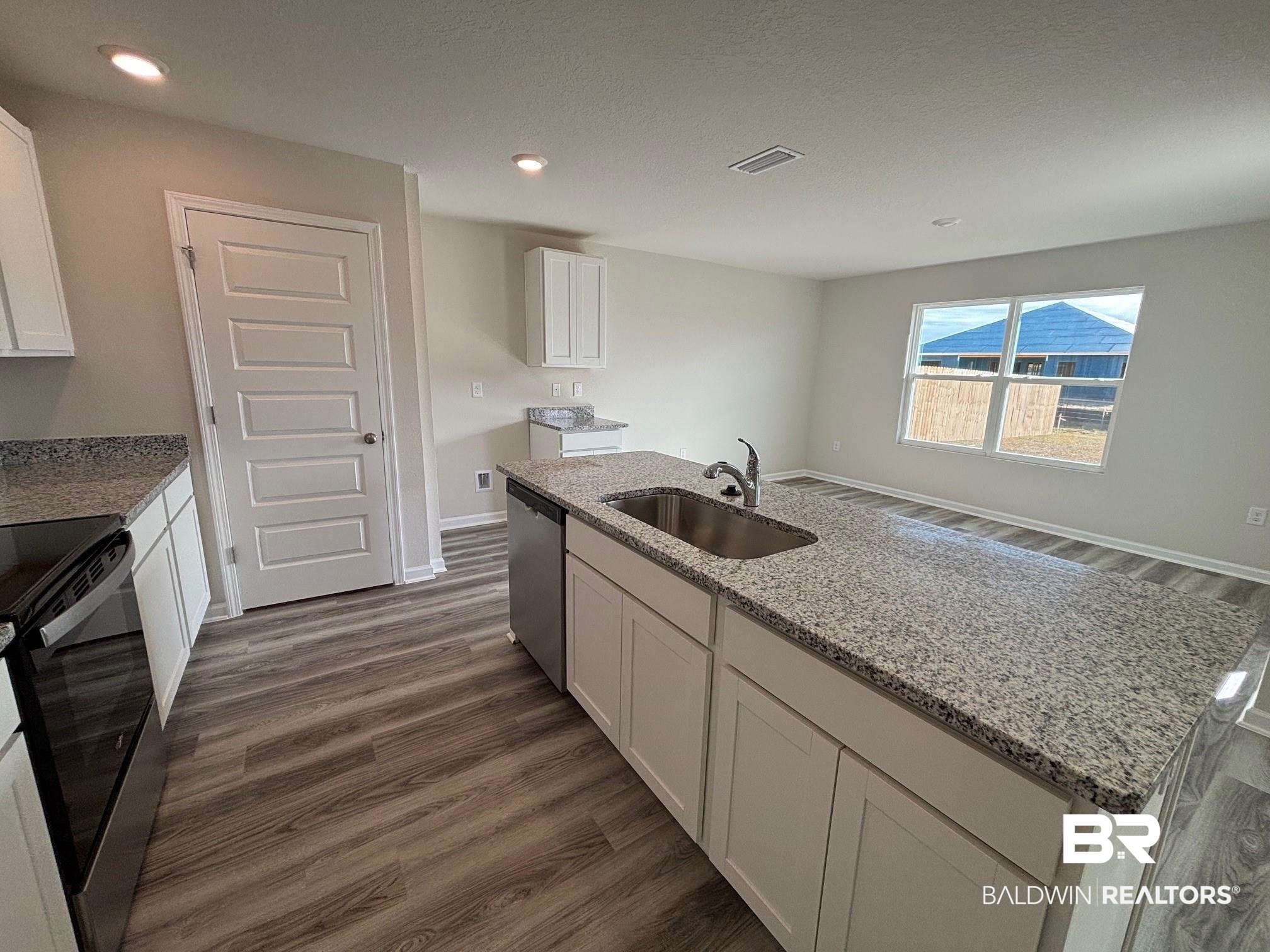 22044 Aleutian Avenue Foley, AL 36535 - Photo 5 of 28 Kitchen featuring light stone countertops, black range with electric cooktop, sink, a center island with sink, and white cabinetry