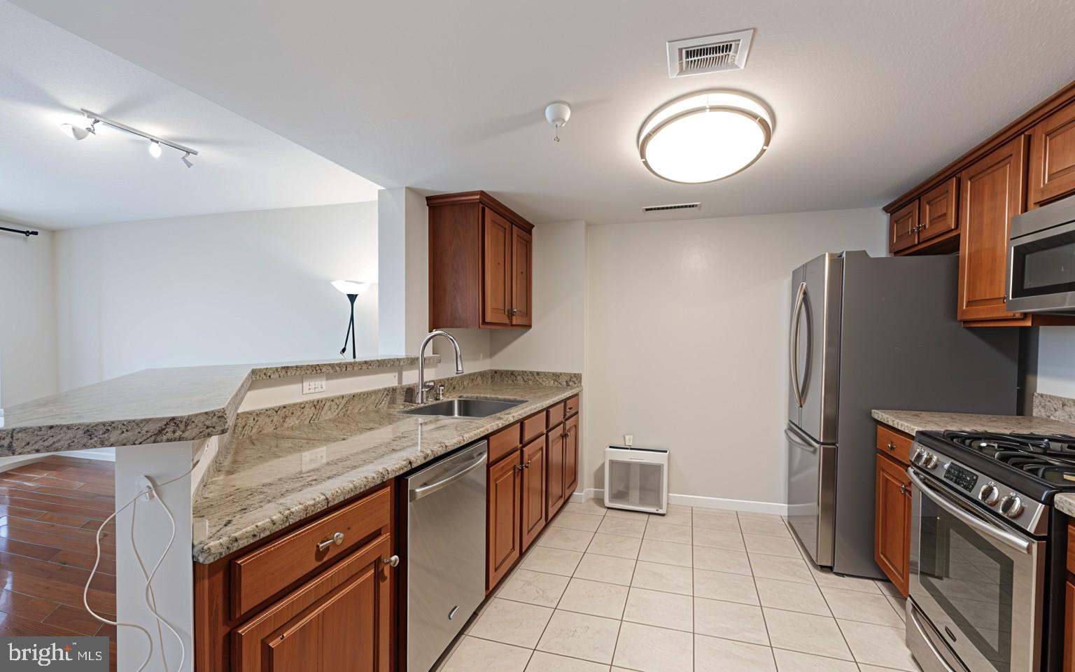 11710 Old Georgetown Road, Unit 1007 North Bethesda, MD 20852 - Photo 11 of 30 a kitchen with granite countertop a sink stainless steel appliances a counter space and cabinets