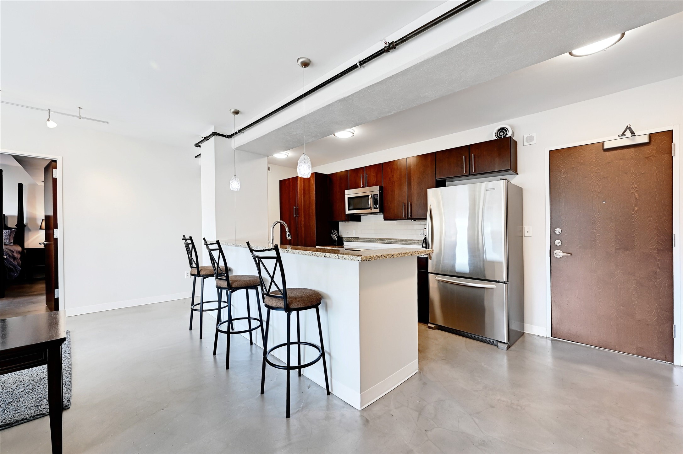 800 Brazos Street, Unit 705 Austin, TX 78701 - Photo 10 of 33 a kitchen with stainless steel appliances kitchen island granite countertop a refrigerator a stove a microwave oven with a dining table and chairs with wooden floor
