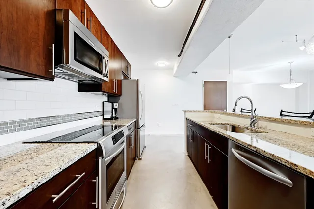 a kitchen with stainless steel appliances granite countertop a sink a stove and a refrigerator