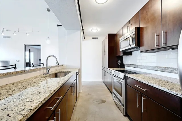 a kitchen with stainless steel appliances granite countertop a refrigerator and a stove top oven