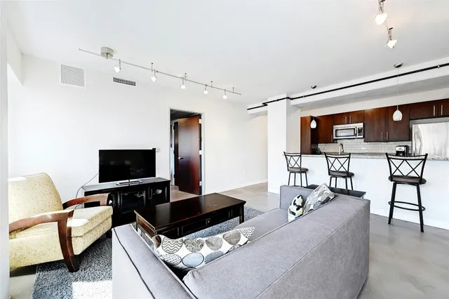 a living room with furniture kitchen view and a chandelier