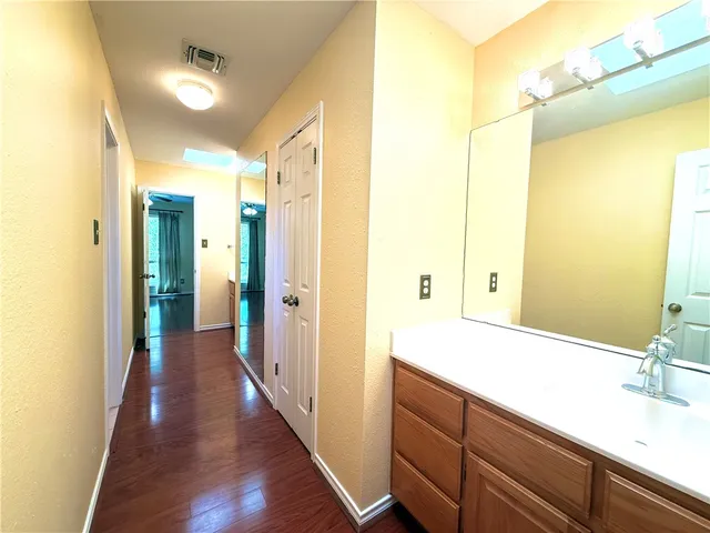 an empty room with wooden floor and fan
