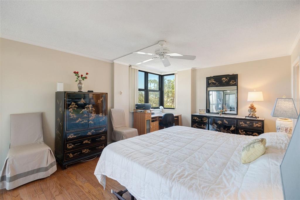 5855 Midnight Pass Road, Unit 318 Sarasota, FL 34242 - Photo 15 of 40 a bedroom with a bed a dresser and wooden floor