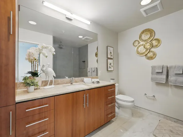 a bathroom with a granite countertop sink a toilet and a mirror