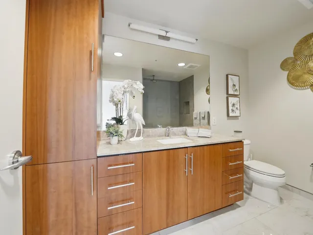 a bathroom with a granite countertop sink a toilet and a mirror