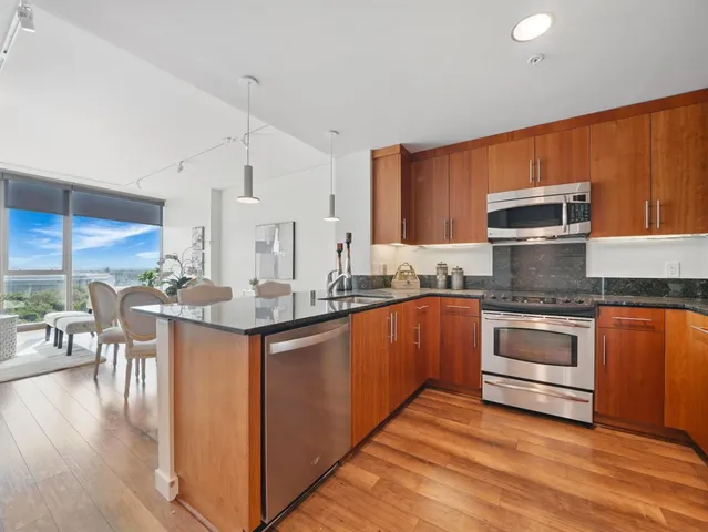 a kitchen with stainless steel appliances kitchen island granite countertop a stove a sink and a refrigerator