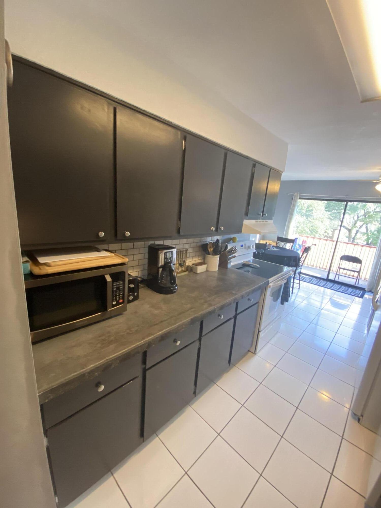 210 Pelham Road, Unit 213A Fort Walton Beach, FL 32547 - Photo 4 of 16 a kitchen with kitchen island granite countertop a sink cabinets and appliances