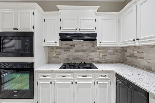 a kitchen with granite countertop a stove sink and cabinets