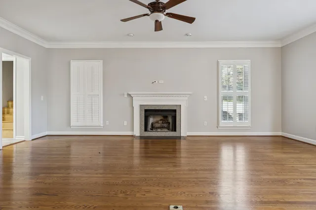 a view of an empty room with wooden floor fireplace and a window