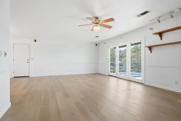a view of an empty room with a window and wooden floor