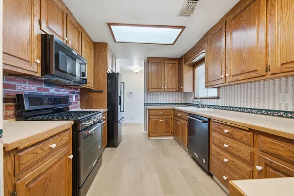 a kitchen with stainless steel appliances granite countertop a stove a sink dishwasher and a refrigerator