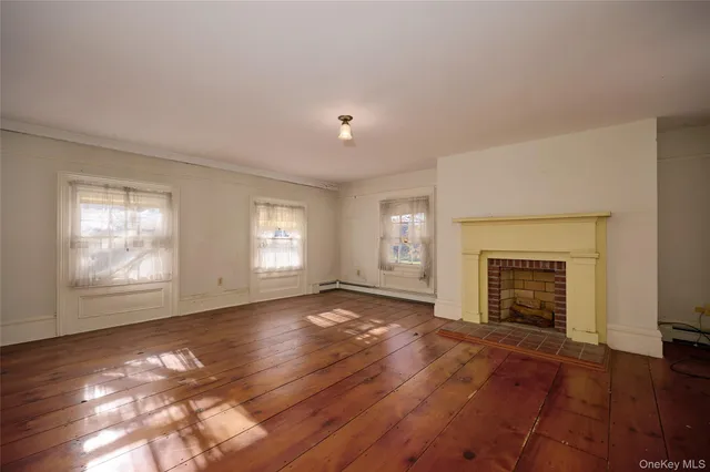 an empty room with windows fireplace and wooden floor