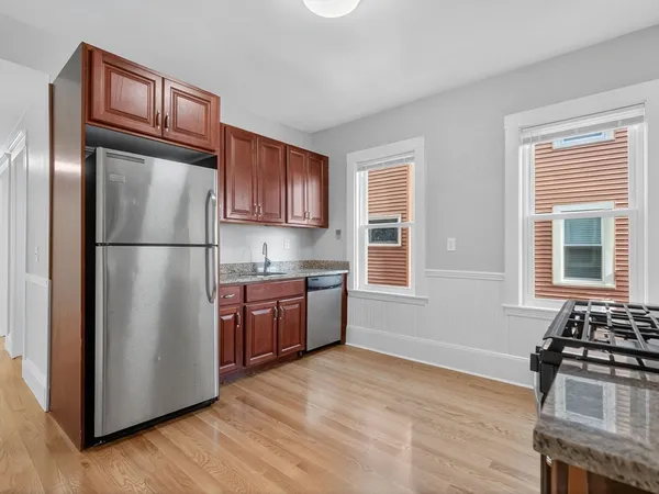 a kitchen with granite countertop stainless steel appliances a refrigerator a stove a sink and a window