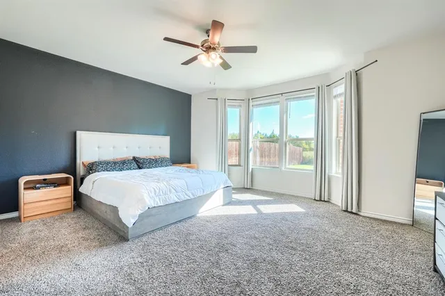 a bedroom with a large bed and a ceiling fan
