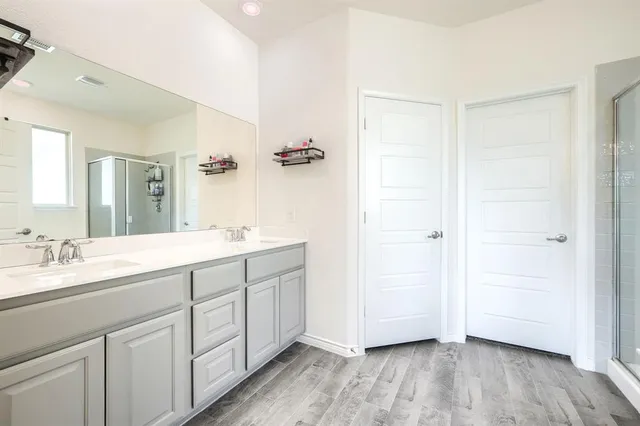 a spacious bathroom with a double vanity sink a mirror and a shower