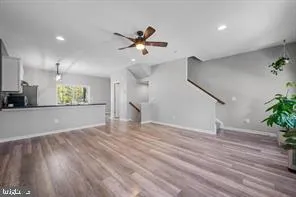 a view of an empty room with wooden floor and a ceiling fan
