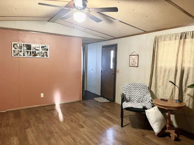 a view of an empty room with wooden floor and chair
