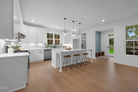 a living room with couches and kitchen view with wooden floor