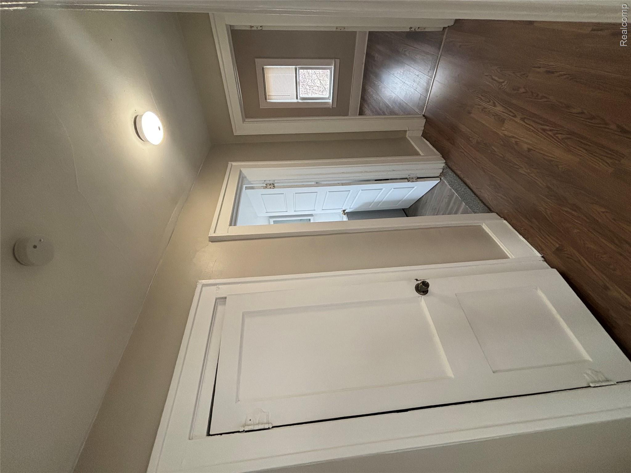 4740-4742 Alter Road Detroit, MI 48215 - Photo 17 of 20 Bright hallway featuring rich wood-finish flooring, multiple white panel doors with hardware, recessed ceiling lighting, and neutral wall finishes throughout