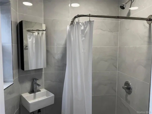 a bathroom with a shower a sink and mirror