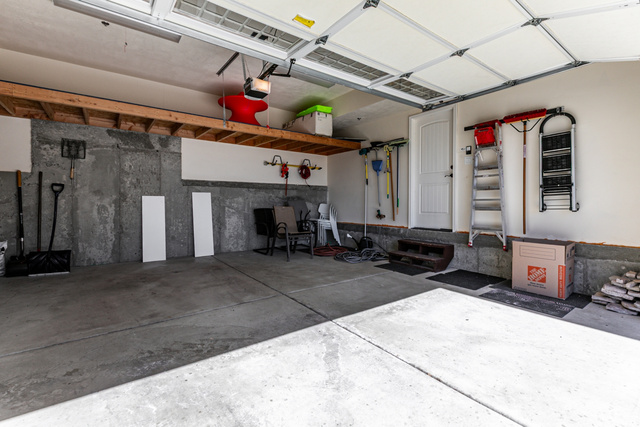 5326 North Oldgate Road Heber City, UT 84032 - Photo 27 of 32 Spacious garage featuring concrete flooring, an overhead garage door, built-in overhead storage shelving, and a pedestrian door