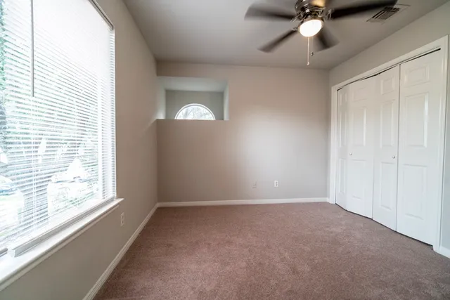 an empty room with a window and a fan