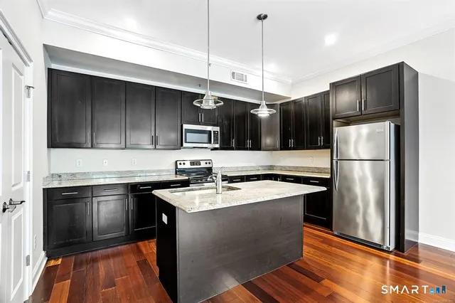 a kitchen with stainless steel appliances granite countertop a sink a stove a refrigerator and island