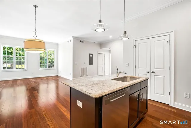 a kitchen with a sink chandelier and wooden floor