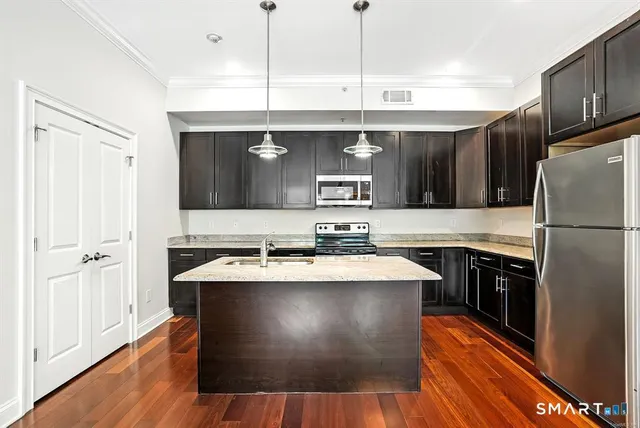 a kitchen with stainless steel appliances granite countertop a sink a stove and a refrigerator