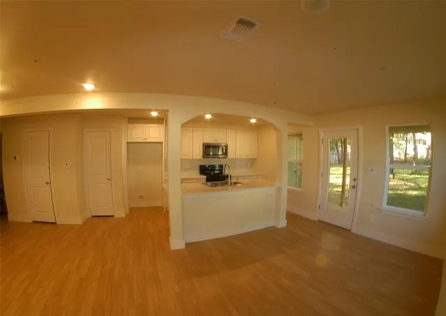 a view of a hallway with wooden floor and a living room