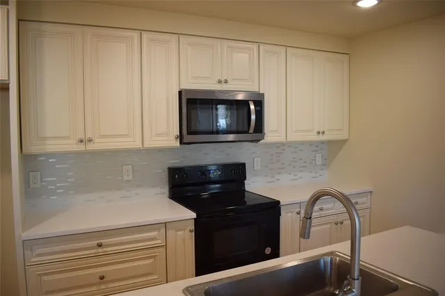 a kitchen with granite countertop white cabinets and stainless steel appliances