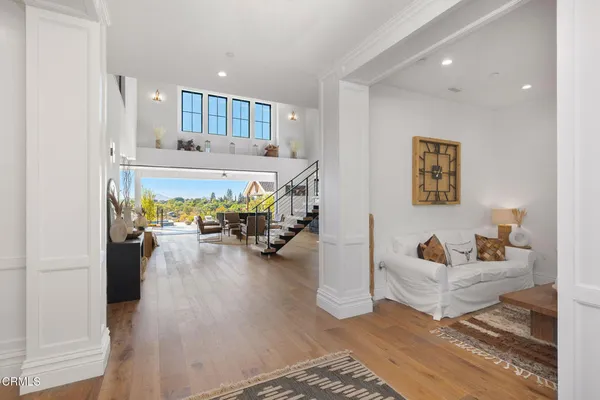 a living room with furniture kitchen view and a wooden floor