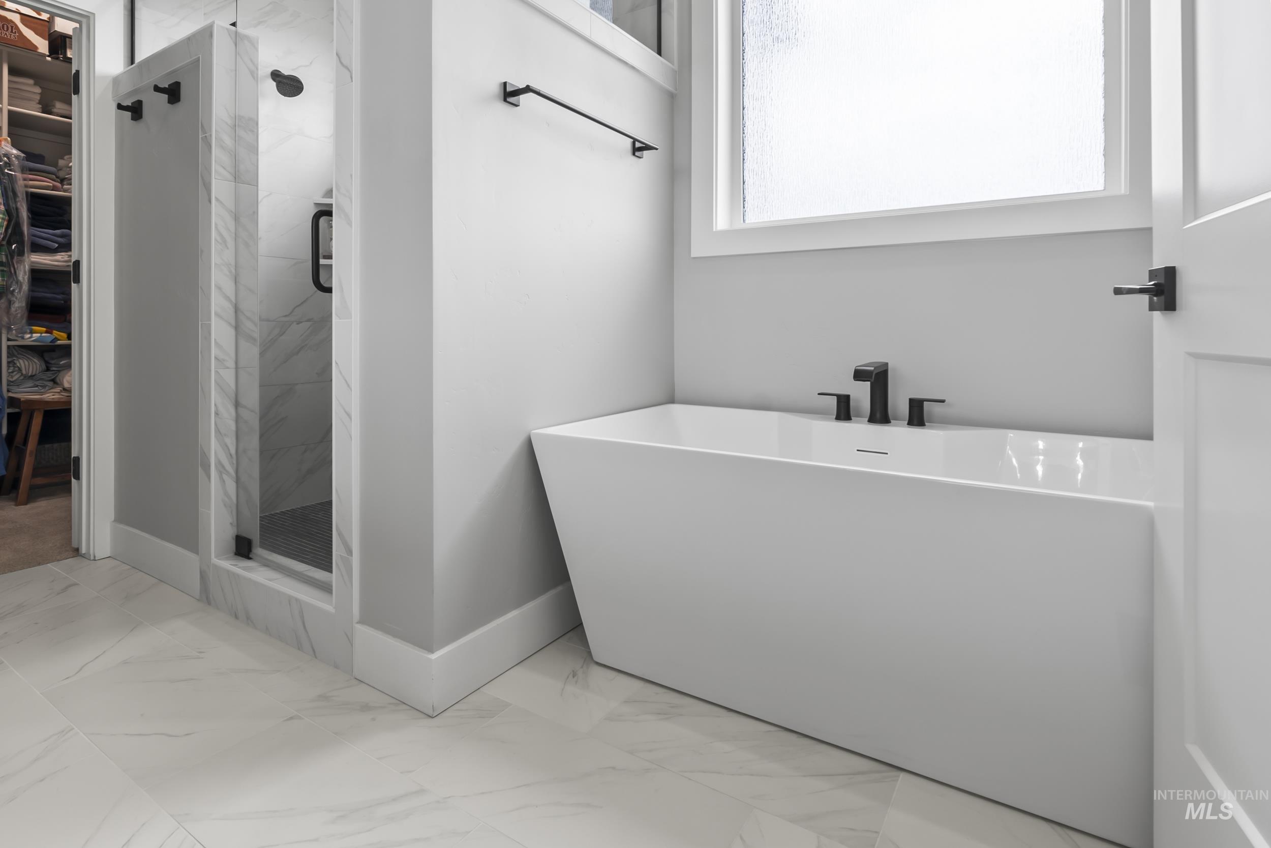 24696 Regal Road Middleton, ID 83644 - Photo 12 of 24 Bathroom with light marble finish floors, a marble finish shower, a walk in closet, and a soaking tub