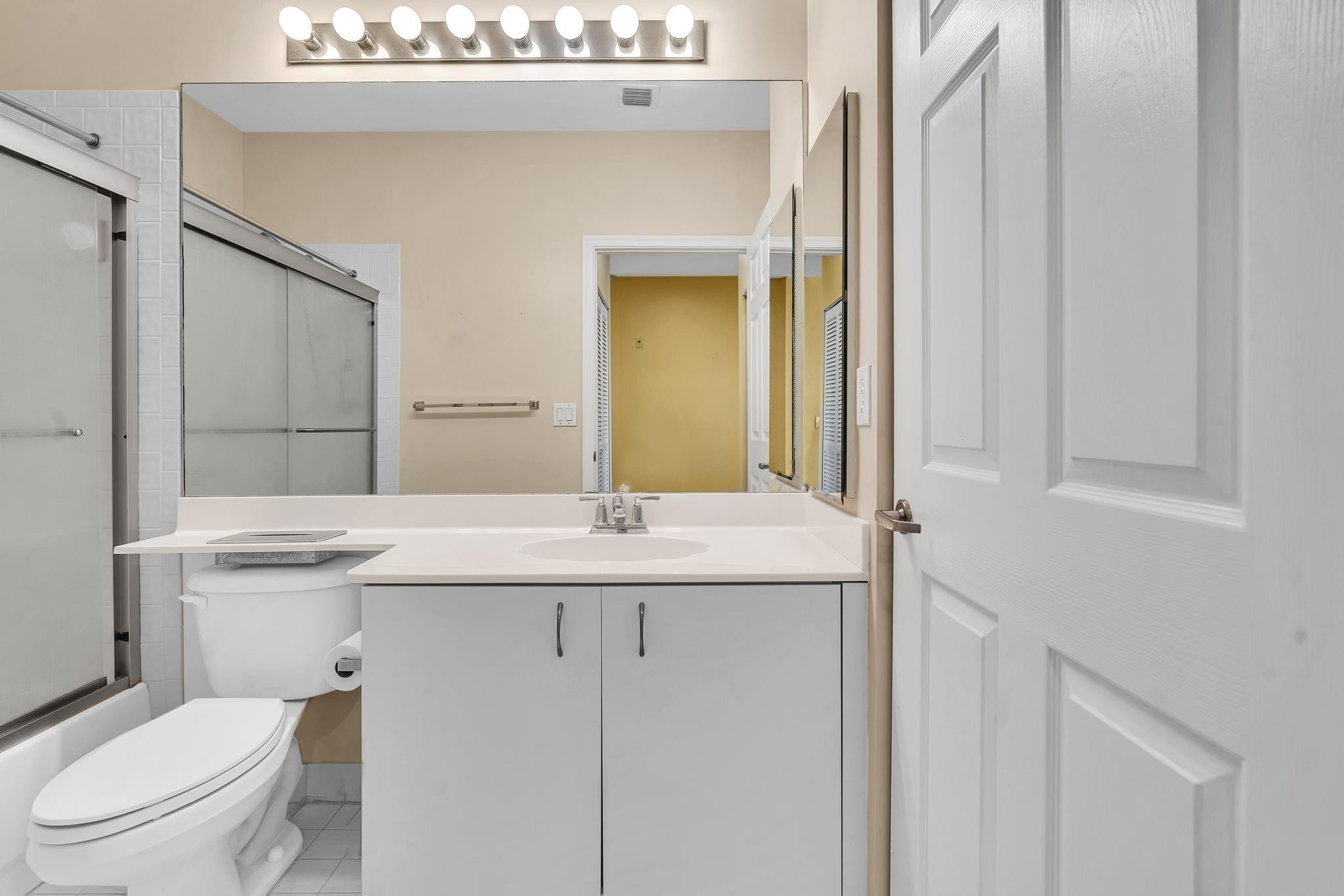 9551 Weldon Circle, Unit E411 Tamarac, FL 33321 - Photo 27 of 78 a bathroom with a granite countertop toilet sink and mirror