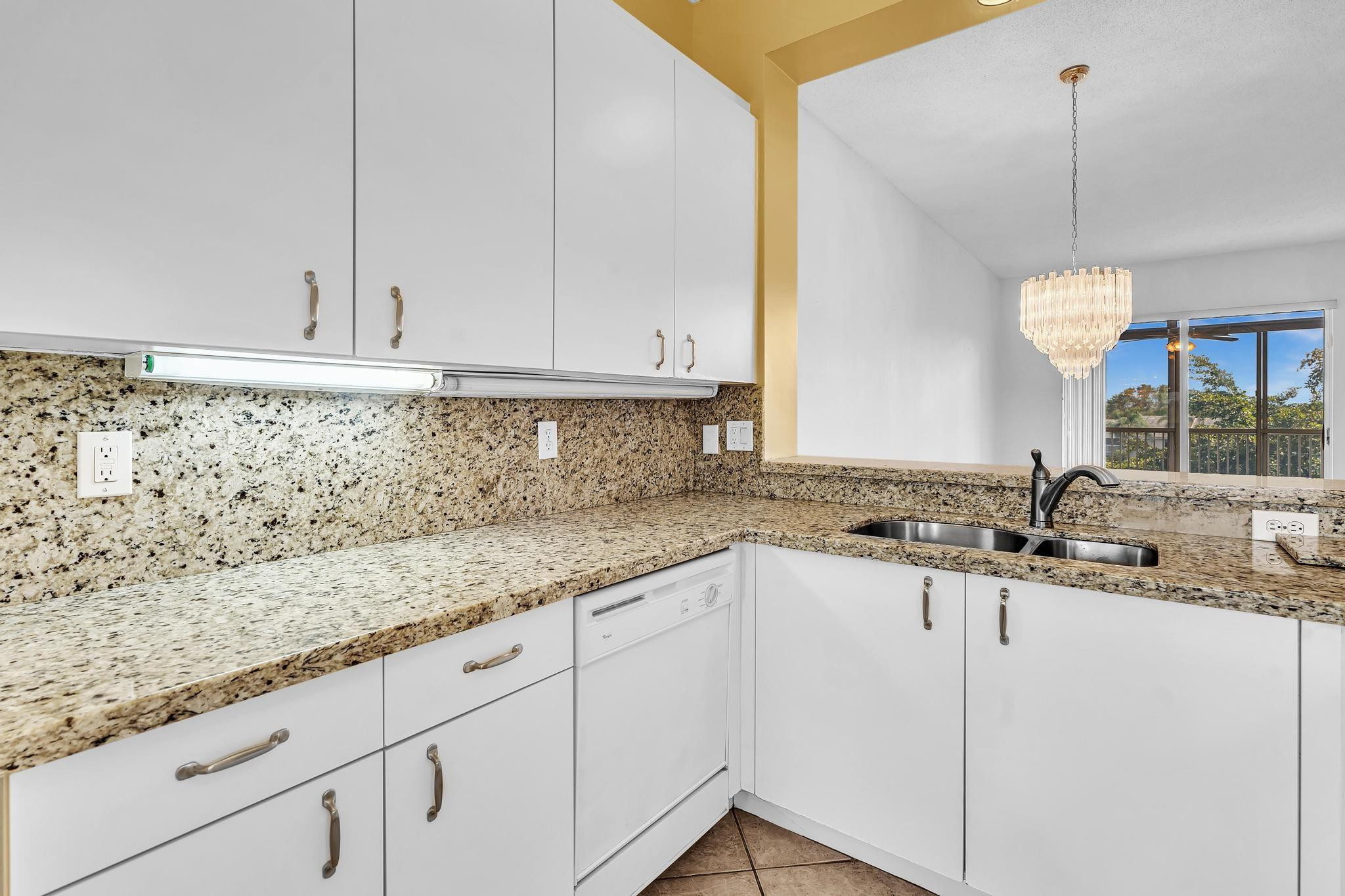 9551 Weldon Circle, Unit E411 Tamarac, FL 33321 - Photo 4 of 78 a kitchen with granite countertop white cabinets and white appliances