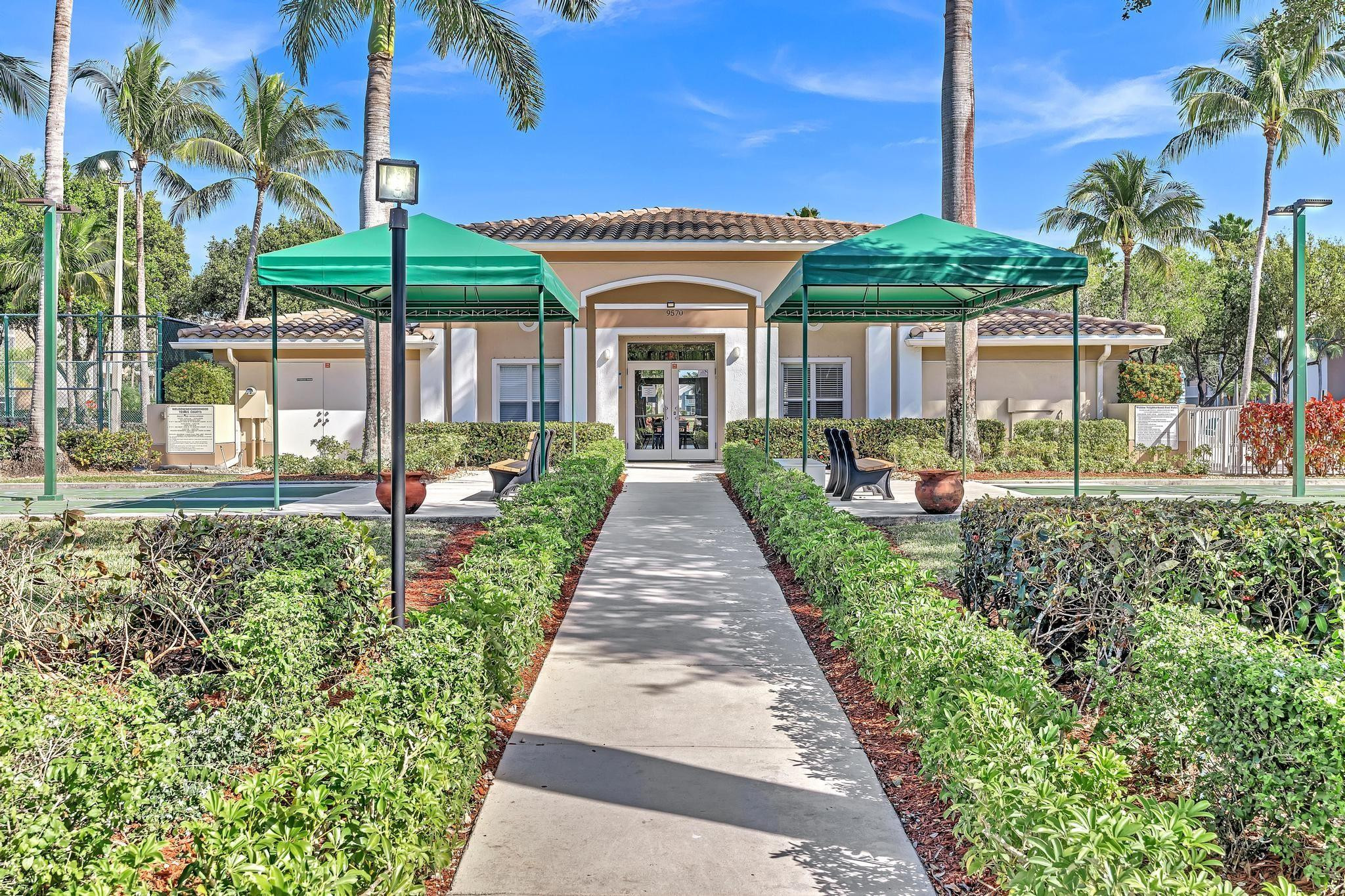 9551 Weldon Circle, Unit E411 Tamarac, FL 33321 - Photo 41 of 78 a front view of a house with a yard and potted plants