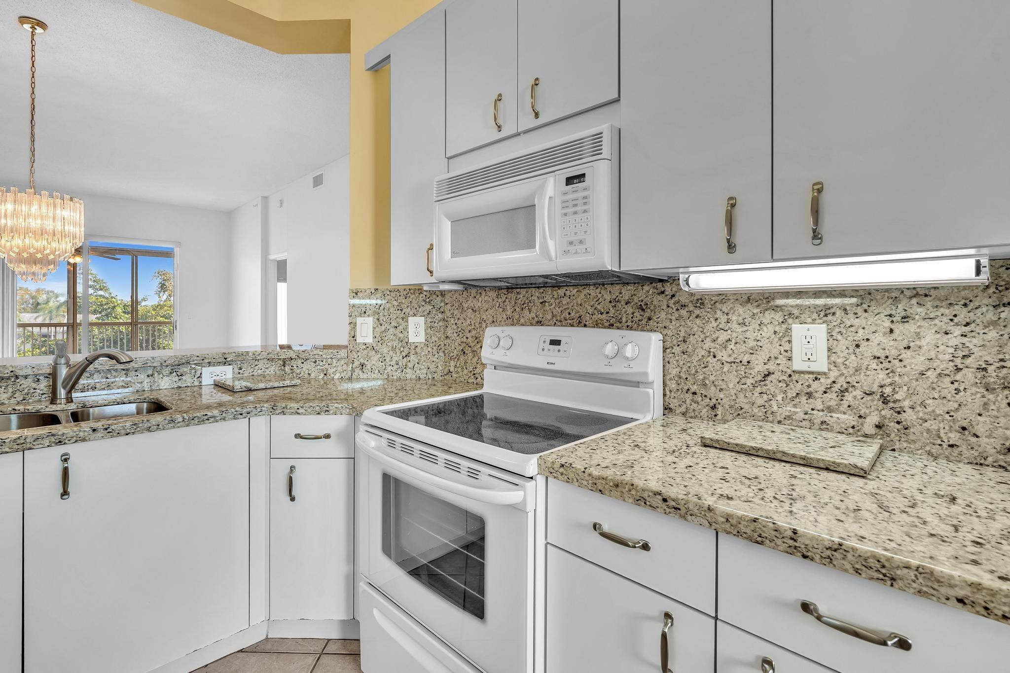 9551 Weldon Circle, Unit E411 Tamarac, FL 33321 - Photo 6 of 78 a kitchen with granite countertop white cabinets sink and stainless steel appliances