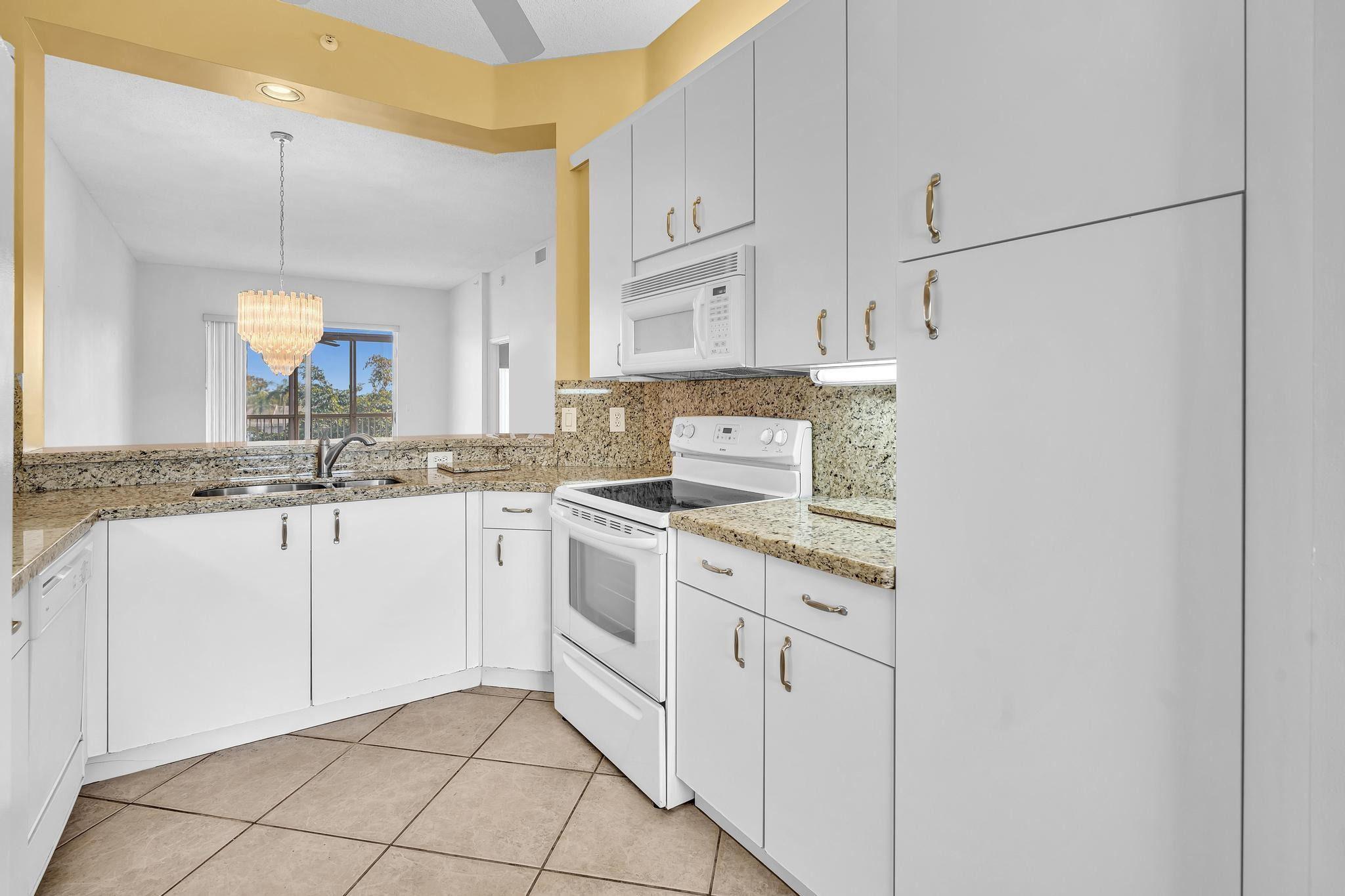 9551 Weldon Circle, Unit E411 Tamarac, FL 33321 - Photo 8 of 78 a kitchen with granite countertop white cabinets and white appliances