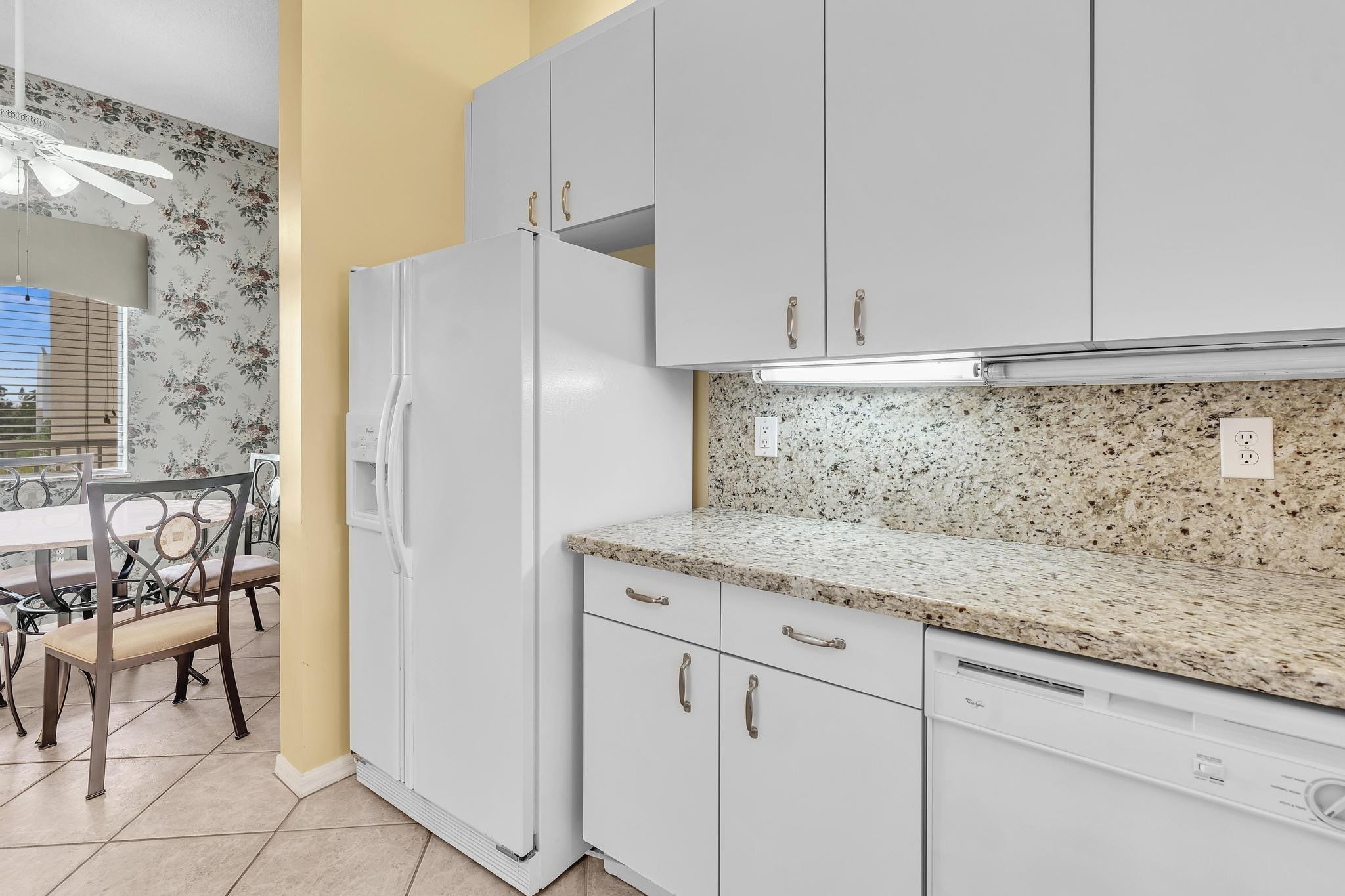 9551 Weldon Circle, Unit E411 Tamarac, FL 33321 - Photo 9 of 78 a kitchen with granite countertop white cabinets and white appliances