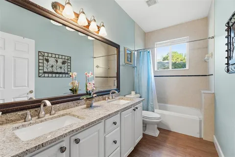 a bathroom with a granite countertop sink a toilet a mirror and shower