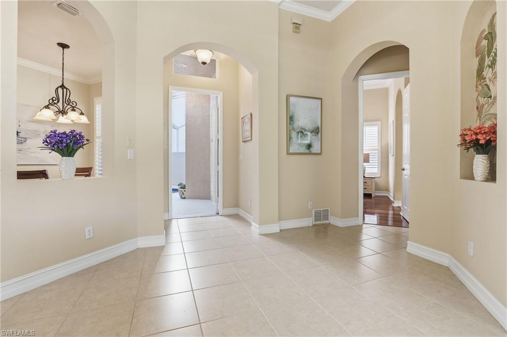 1769 Sanctuary Pointe Court Naples, FL 34110 - Photo 5 of 40 a view of a hallway with wooden floor and a chandelier