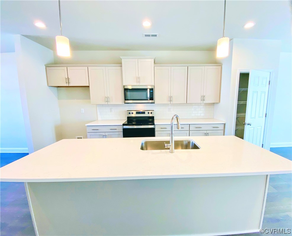 7001 Dunton Road Chesterfield, VA 23832 - Photo 12 of 28 a kitchen with kitchen island a stove a sink a refrigerator and white cabinets with wooden floor