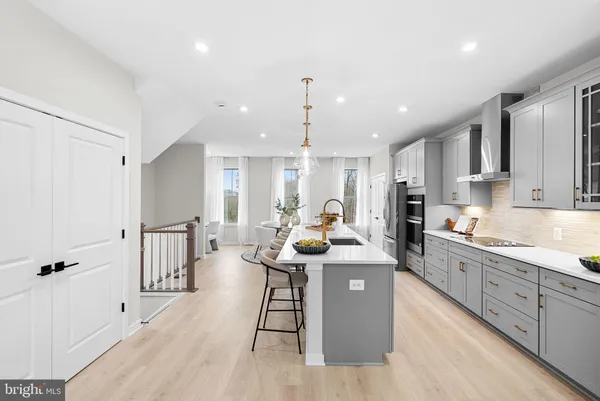 a large kitchen with stainless steel appliances kitchen island granite countertop a lot of counter space and a wooden floor